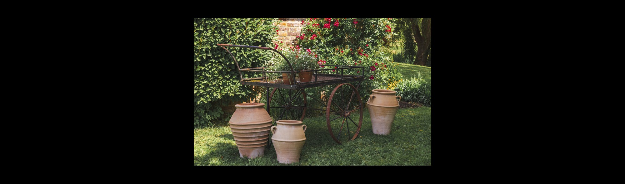 Metal barrow with ceramic pots in a garden