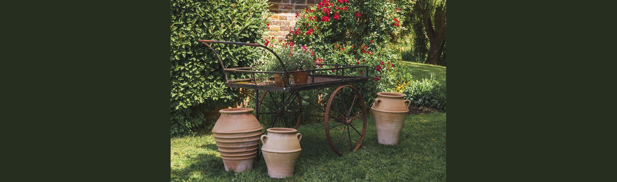 Metal barrow with ceramic pots in a garden