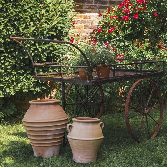 Metal barrow with ceramic pots in a garden