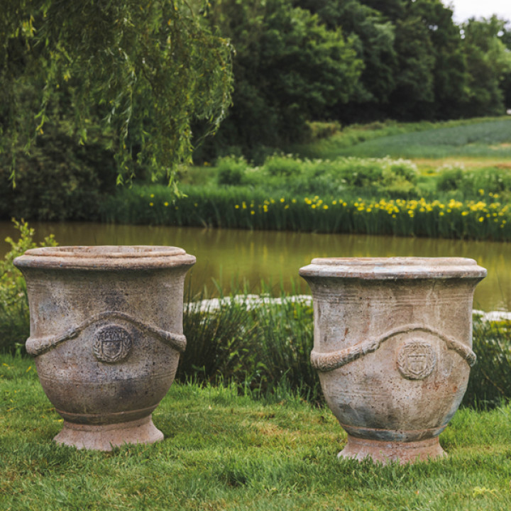 Two terracotta urns in garden setting Two terracotta urns in garden setting
