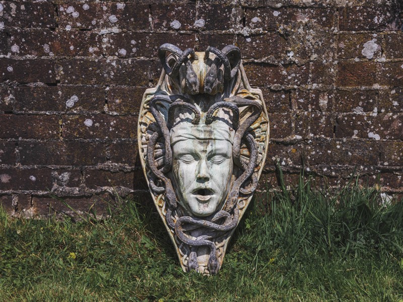 Sculpture of head surrounded by snakes against a garden wall Sculpture of head surrounded by snakes against a garden wall